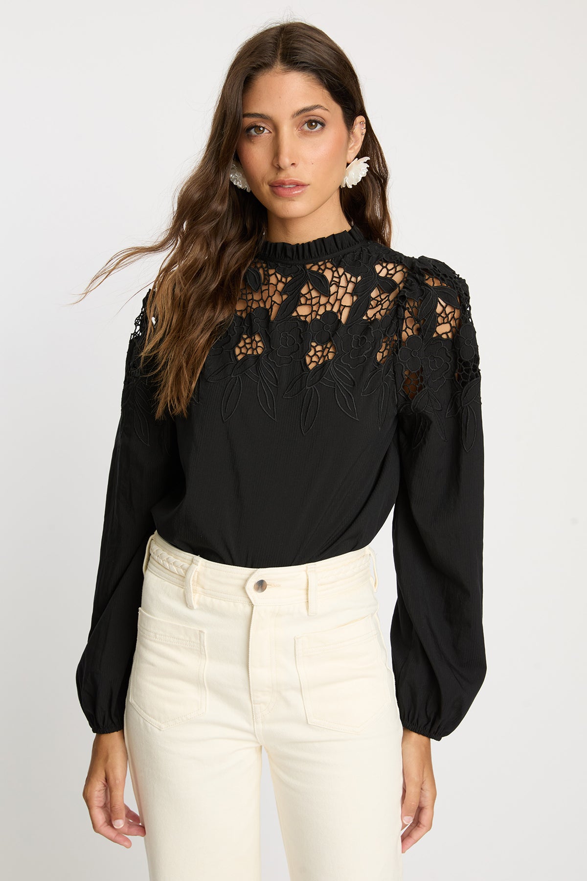 Woman wearing a black blouse with floral lace details on a white background