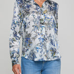 Woman wearing a floral blouse with blue jeans on a gray background