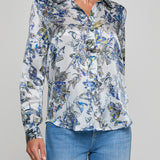 Woman wearing a floral blouse with blue jeans on a gray background