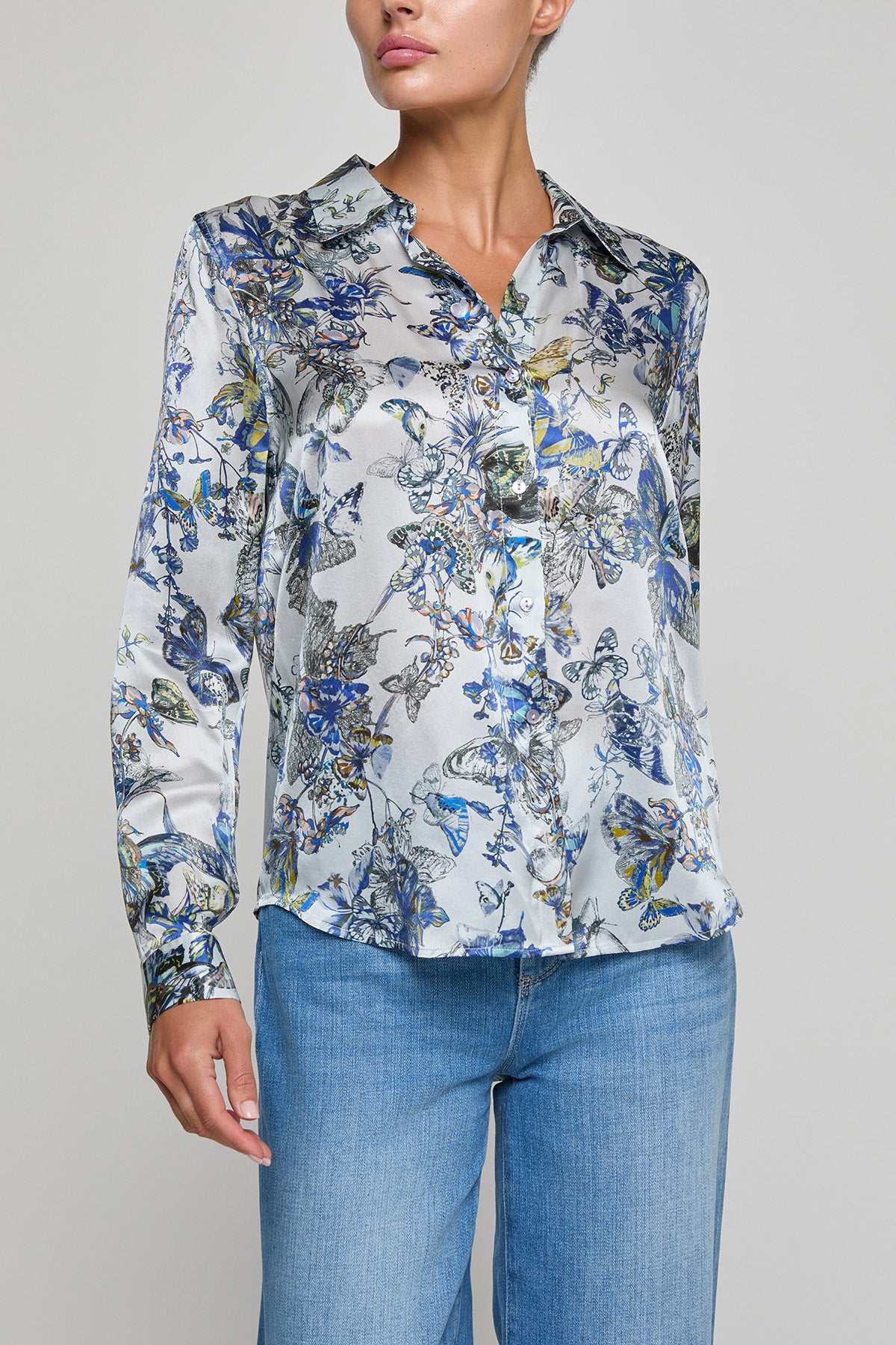Woman wearing a floral blouse with blue jeans on a gray background