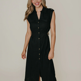 Model wearing a sleeveless black midi dress with a tailored silhouette and subtle front detailing, photographed against a neutral studio background.