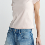 Person wearing a light pink t-shirt and blue denim shorts on a white background