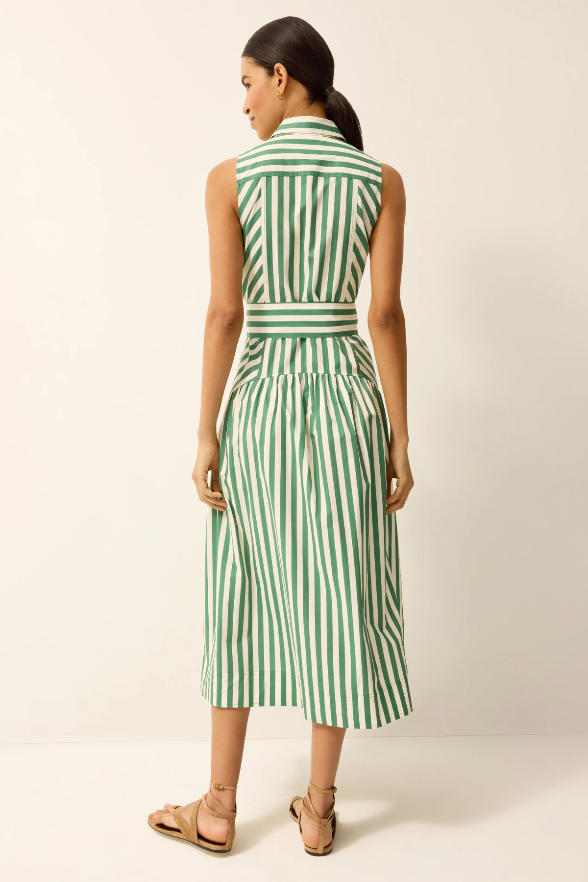 Woman wearing a green and white striped dress against a plain background