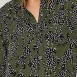 Close-up of a person wearing an olive green button-up shirt with a black and white animal print pattern.