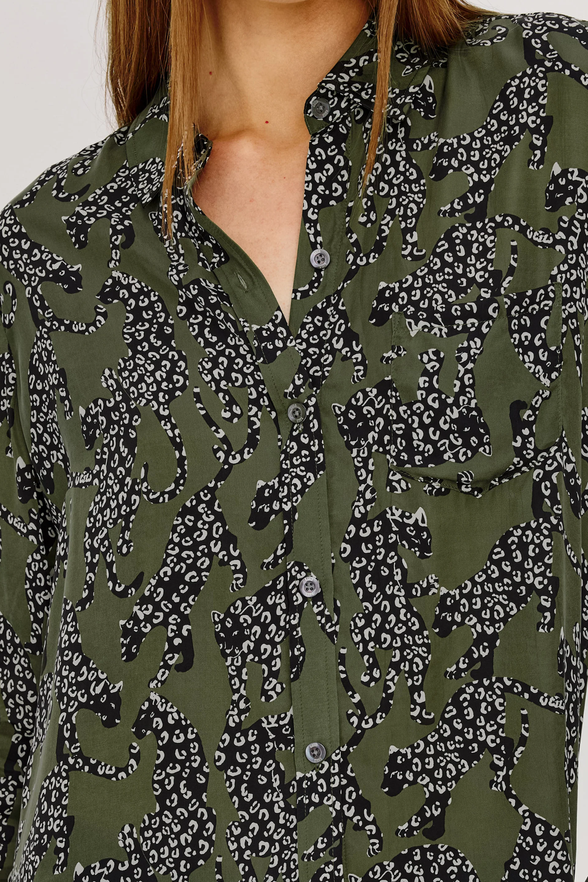 Close-up of a person wearing an olive green button-up shirt with a black and white animal print pattern.