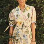 Woman wearing a floral dress standing in front of green foliage