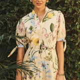 Woman wearing a floral dress standing in front of green foliage