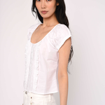 Woman wearing a white blouse against a plain background