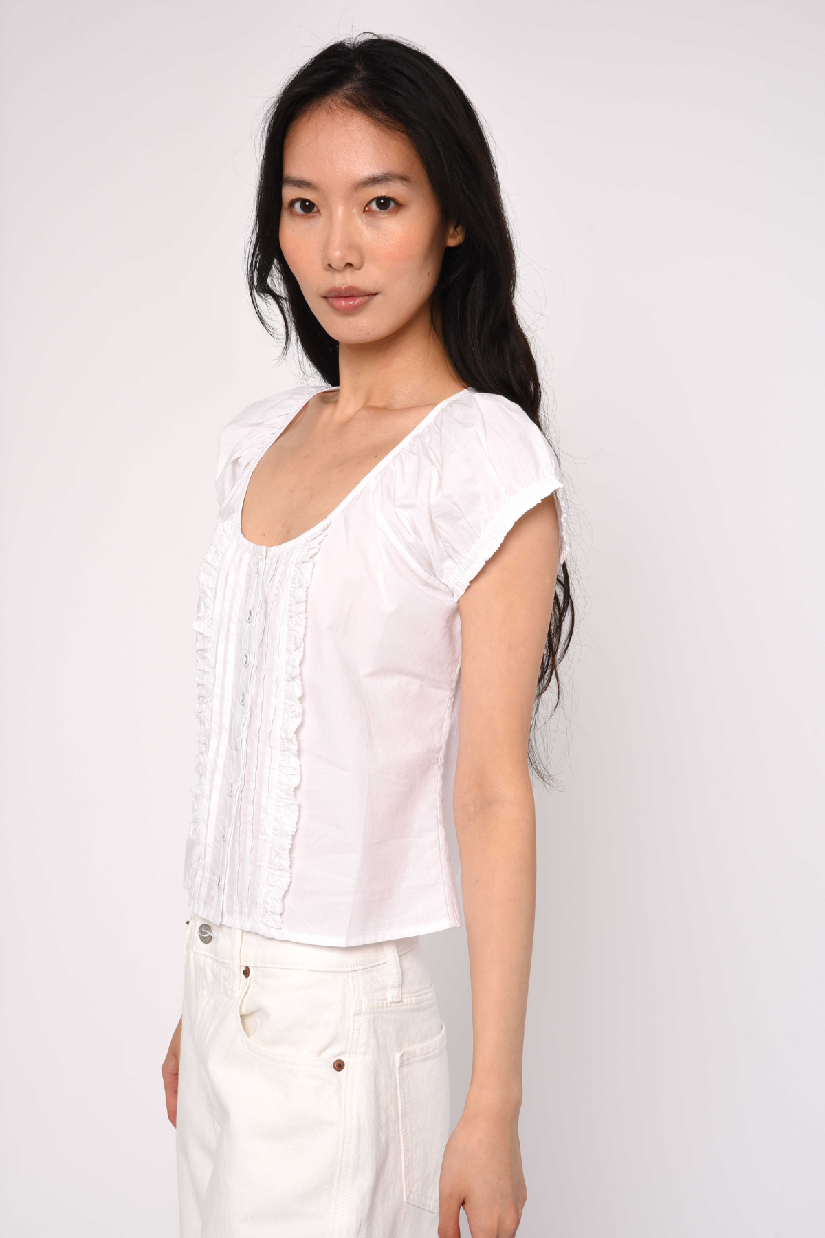 Woman wearing a white blouse against a plain background