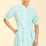 Woman wearing a light blue dress with puff sleeves on a beige background