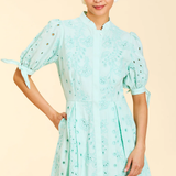 Woman wearing a light blue dress with puff sleeves on a beige background