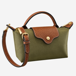 An olive green canvas handbag with brown leather trim, a top handle, a detachable shoulder strap, and gold-tone hardware, shown on a plain light gray background.