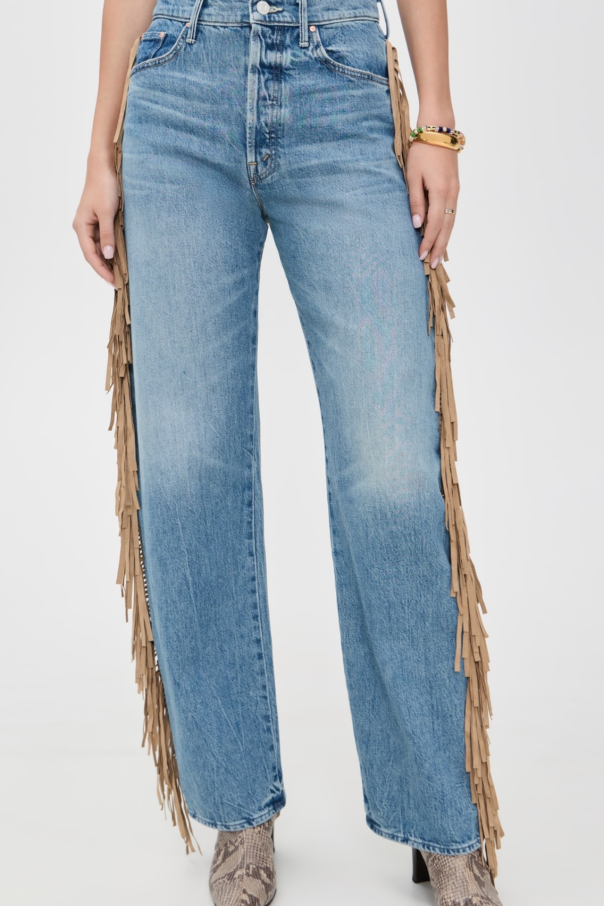 Light blue wide-leg denim jeans with long tan fringe draped down the outer sides, shown on a model against a plain light background.