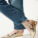 Gold wedge shoes worn with blue jeans on a light background