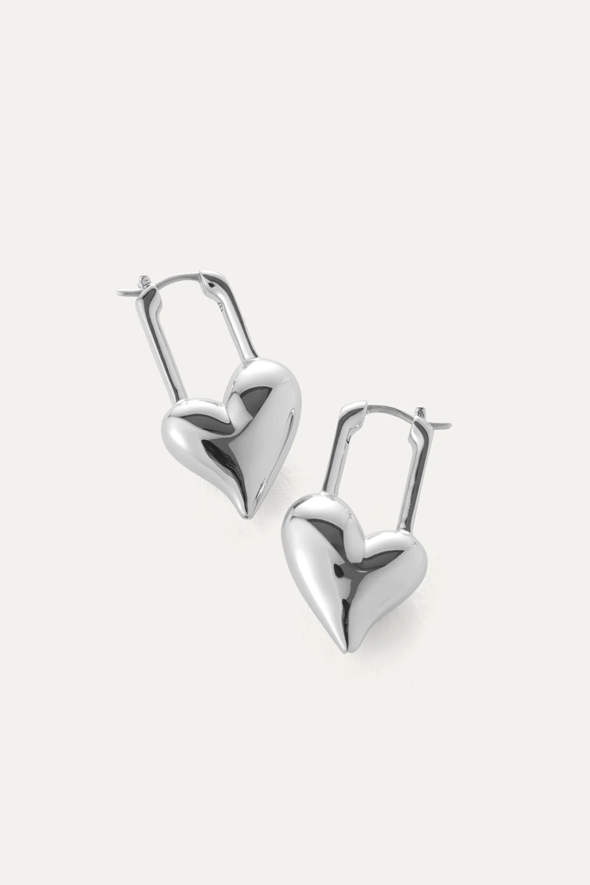 Heart-shaped silver earrings on a light gray background