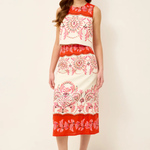 Woman wearing a sleeveless dress with red and white floral pattern on a plain background