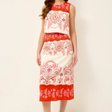 Woman wearing a sleeveless dress with red and white floral pattern on a plain background