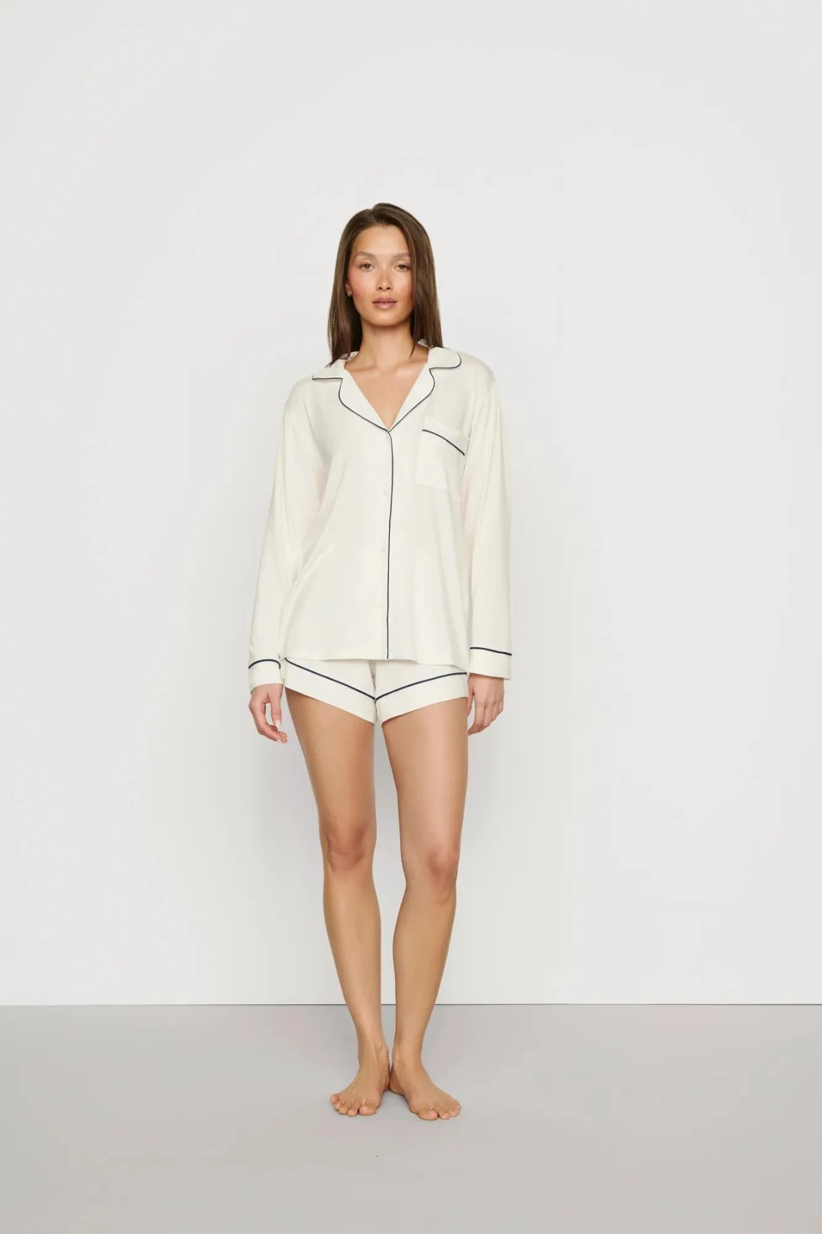 Woman wearing a white pajama set against a plain background