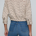 Model wearing a tweed jacket with jeans on and off white background.