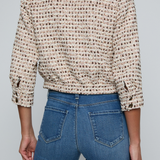 Model wearing a tweed jacket with jeans on and off white background.