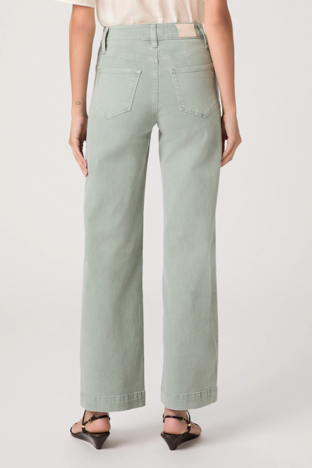 Person wearing light green wide-leg jeans on a plain background