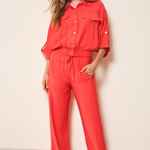 Woman wearing a red set standing against a plain wall.