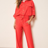Woman wearing a red set standing against a plain wall.