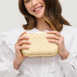 Woman holding a woven beige clutch against a white background