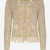 A cropped, long-sleeve tweed jacket in a textured champagne beige with gold buttons and fringe detailing, shown against a plain light gray background.