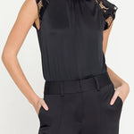Black sleeveless top with lace details and black pants on a white background