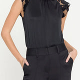 Black sleeveless top with lace details and black pants on a white background