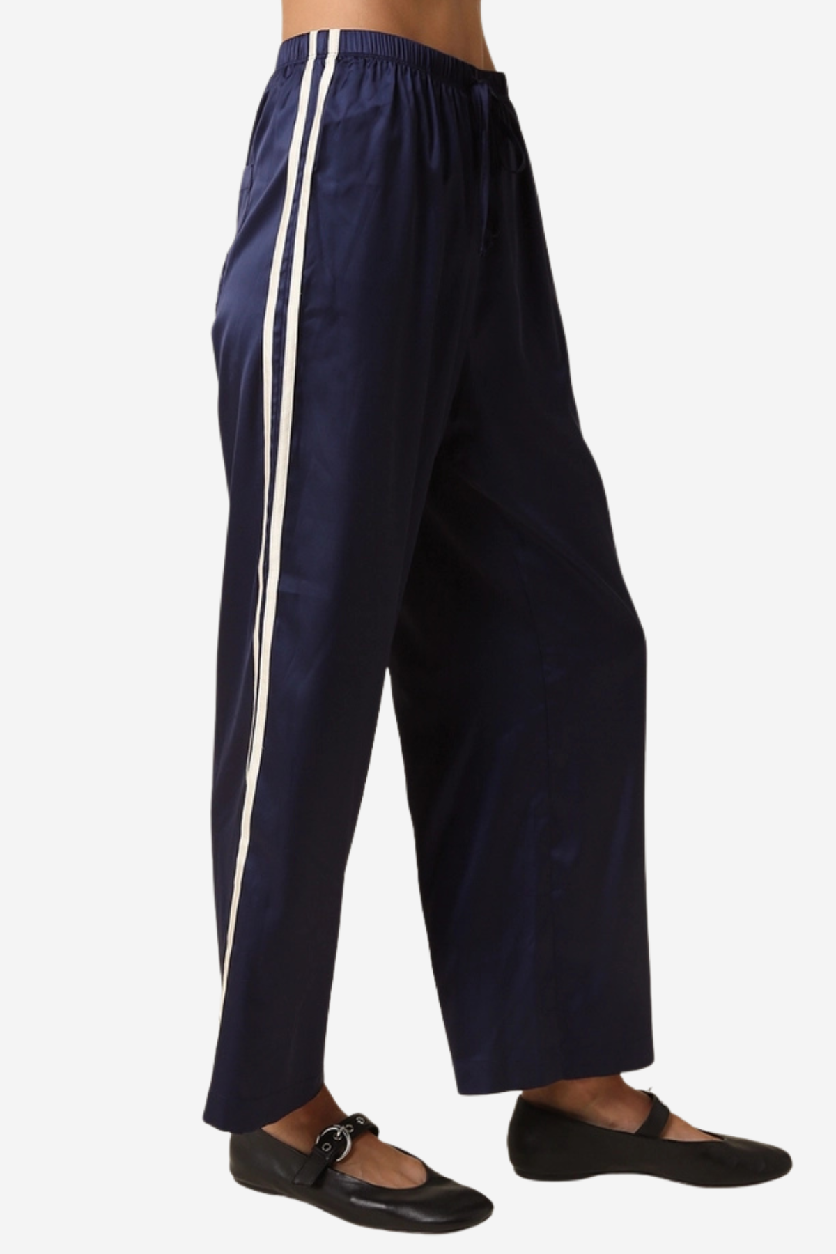 A person wearing loose navy wide-leg pants with two vertical white side stripes, paired with black flats, shown against a plain light background.