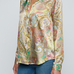 Model wearing printed blouse with jeans on a white background.