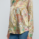Model wearing printed blouse with jeans on a white background.