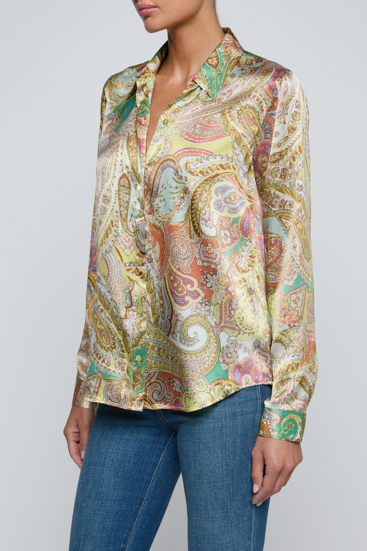 Model wearing printed blouse with jeans on a white background.
