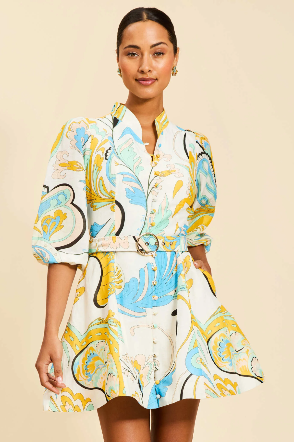 Woman wearing a colorful patterned dress against a beige background