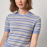 Woman wearing a blue and white striped sweater against a plain background