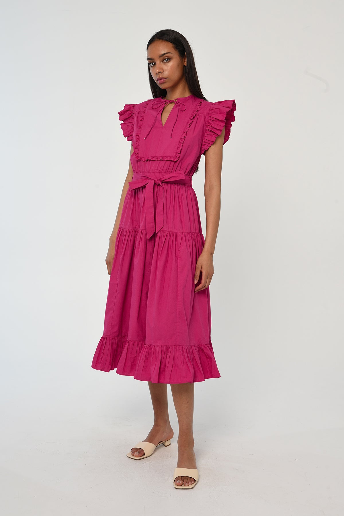 Woman wearing a vibrant pink sleeveless midi dress with soft tailoring and fluid drape.