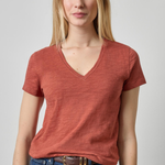 Woman wearing a red t-shirt and blue jeans on a plain background