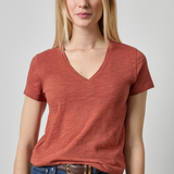 Woman wearing a red t-shirt and blue jeans on a plain background