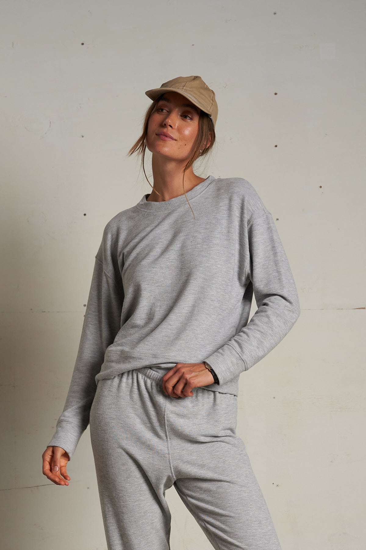 Woman wearing a light grey long-sleeve knit top with a relaxed fit, photographed against a soft neutral backdrop.