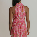 Woman wearing a pink floral dress against a plain background