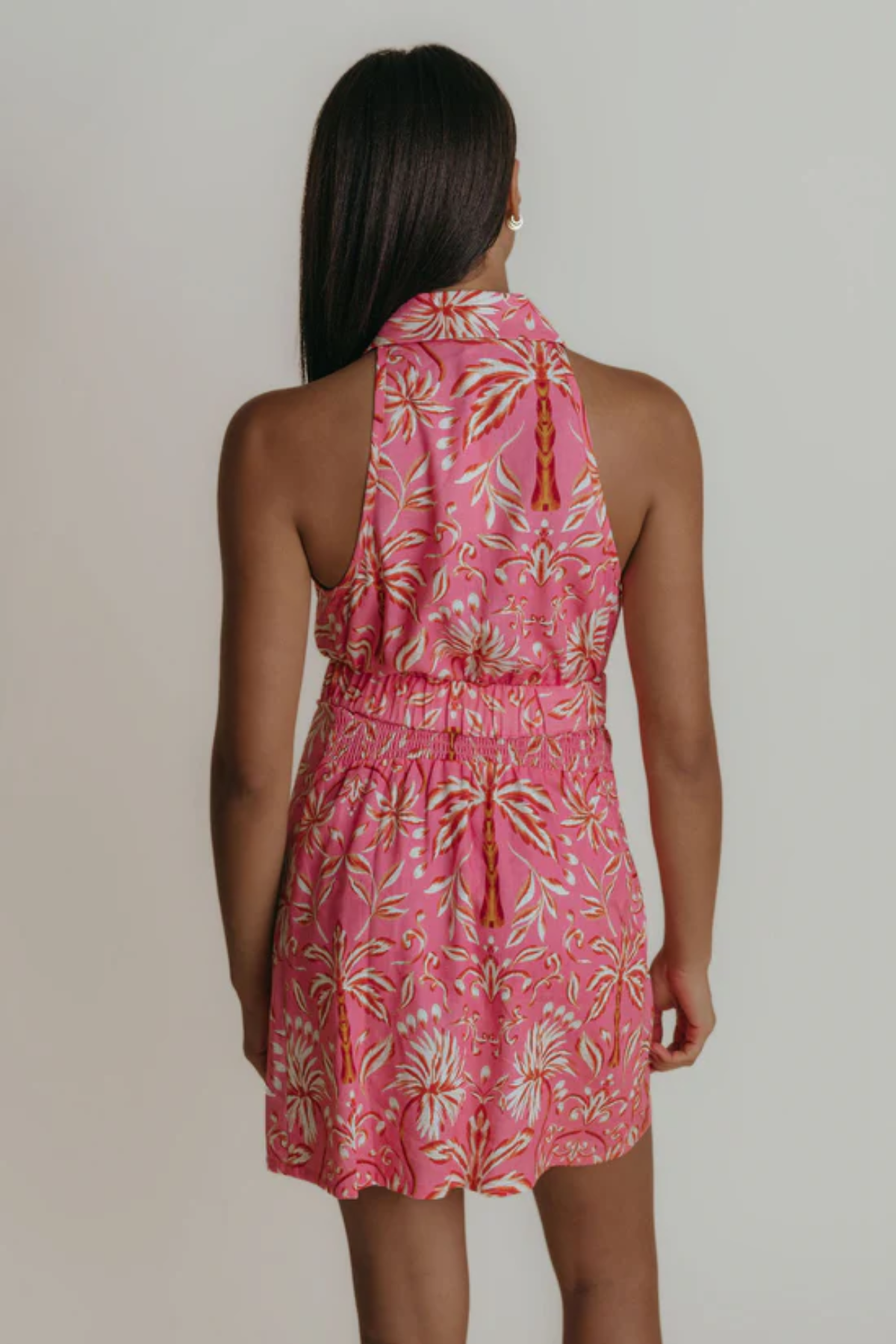 Woman wearing a pink floral dress against a plain background