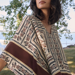 Woman wearing a patterned shawl outdoors with trees in the background