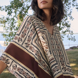 Woman wearing a patterned shawl outdoors with trees in the background
