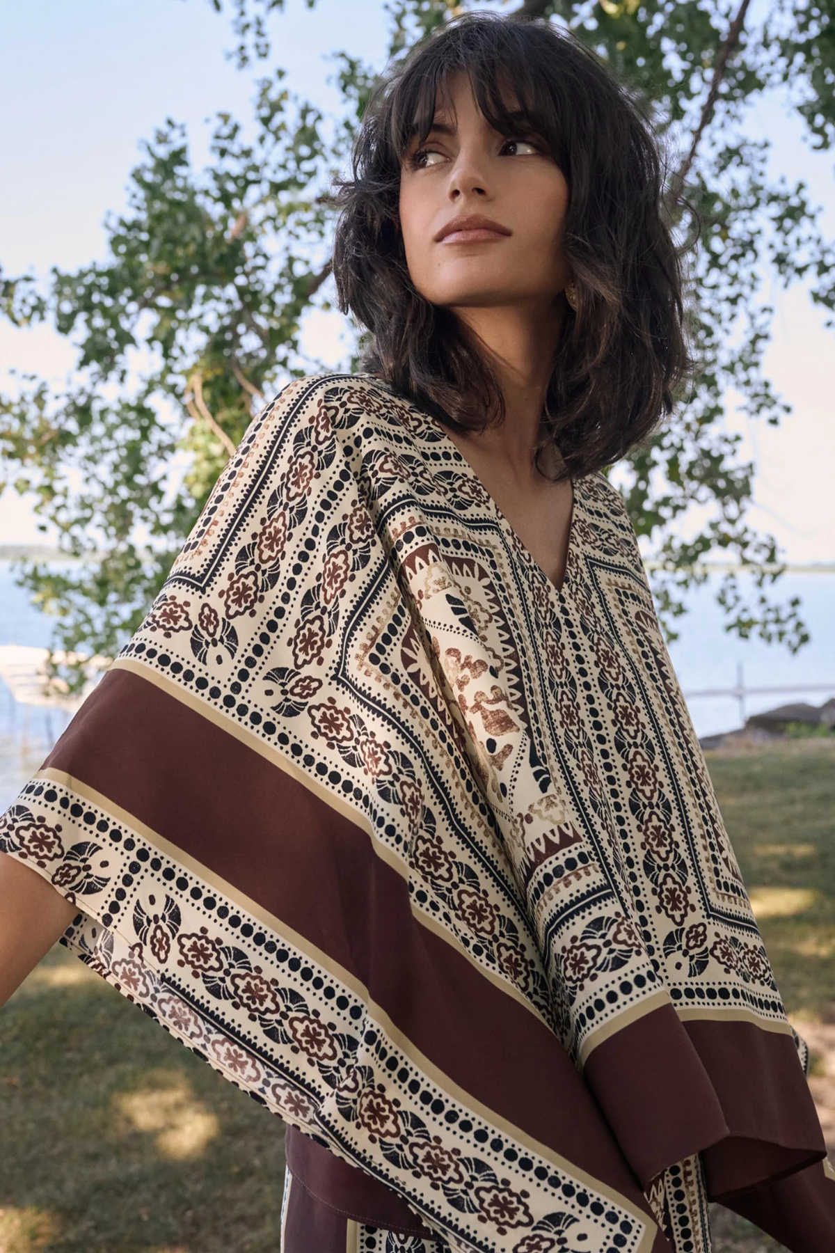 Woman wearing a patterned shawl outdoors with trees in the background