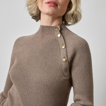 Woman wearing a brown ribbed sweater with gold buttons on a light gray background