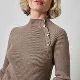 Woman wearing a brown ribbed sweater with gold buttons on a light gray background
