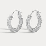 Gold pavé huggie earrings displayed against a warm neutral background