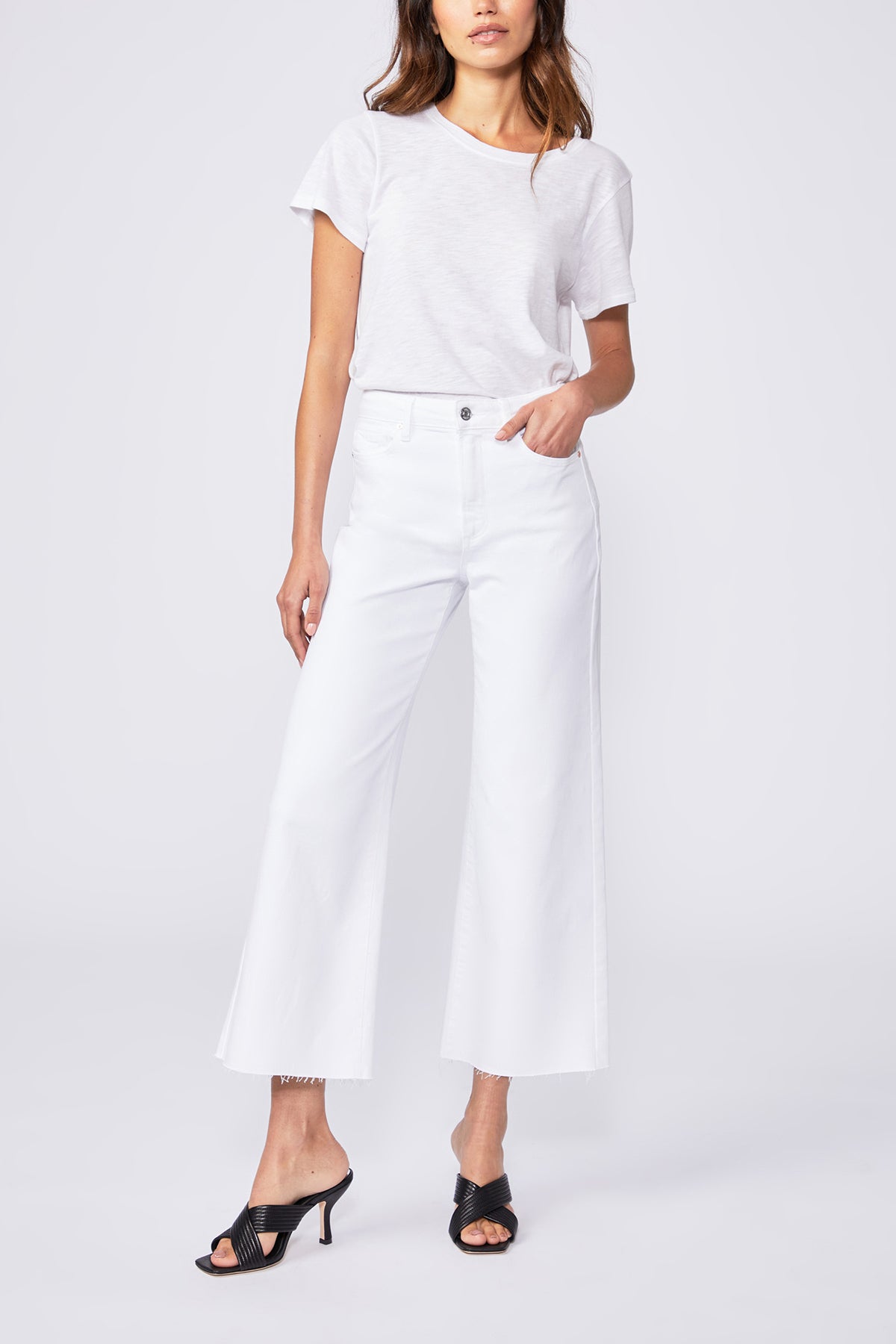 Woman wearing a white outfit with black sandals on a white background